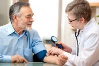 Blood pressure being taken by a doctor in a doctor's office.