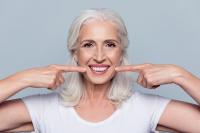 Oral Hygiene woman pointing at her teeth smiling.