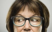 Woman's face from the nose up looking askance through her blue glasses