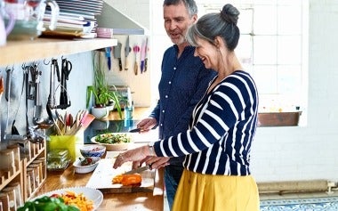 Couple cooking healthy food together in their well-lit kitchen