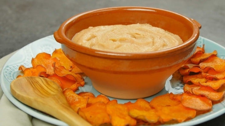 Bowl of white bean hummus surrounded by sweet potato chips 